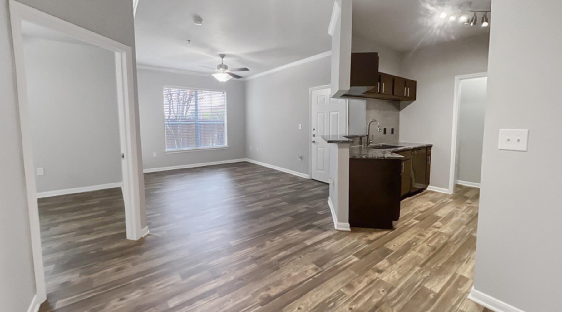 an open room leading into a kitchen and living room with wood floors