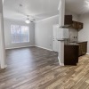 an open room leading into a kitchen and living room with wood floors