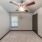 an empty bedroom with a window and ceiling fan