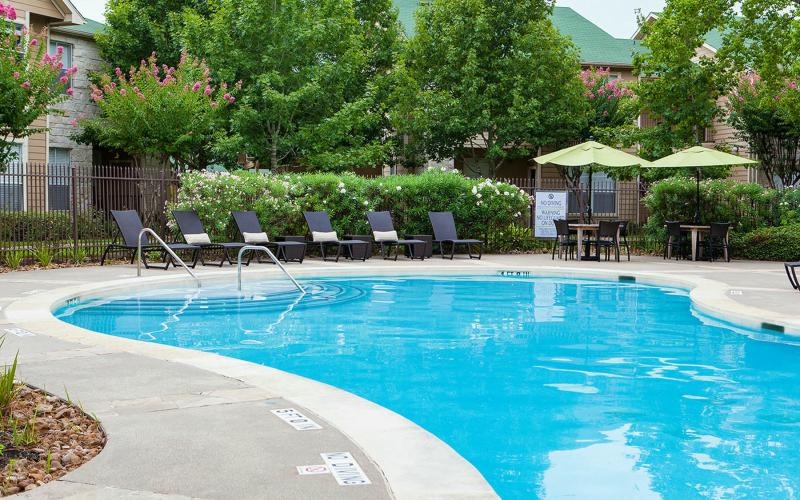 Resort-style swimming pool a pool with lounge chairs and trees around it