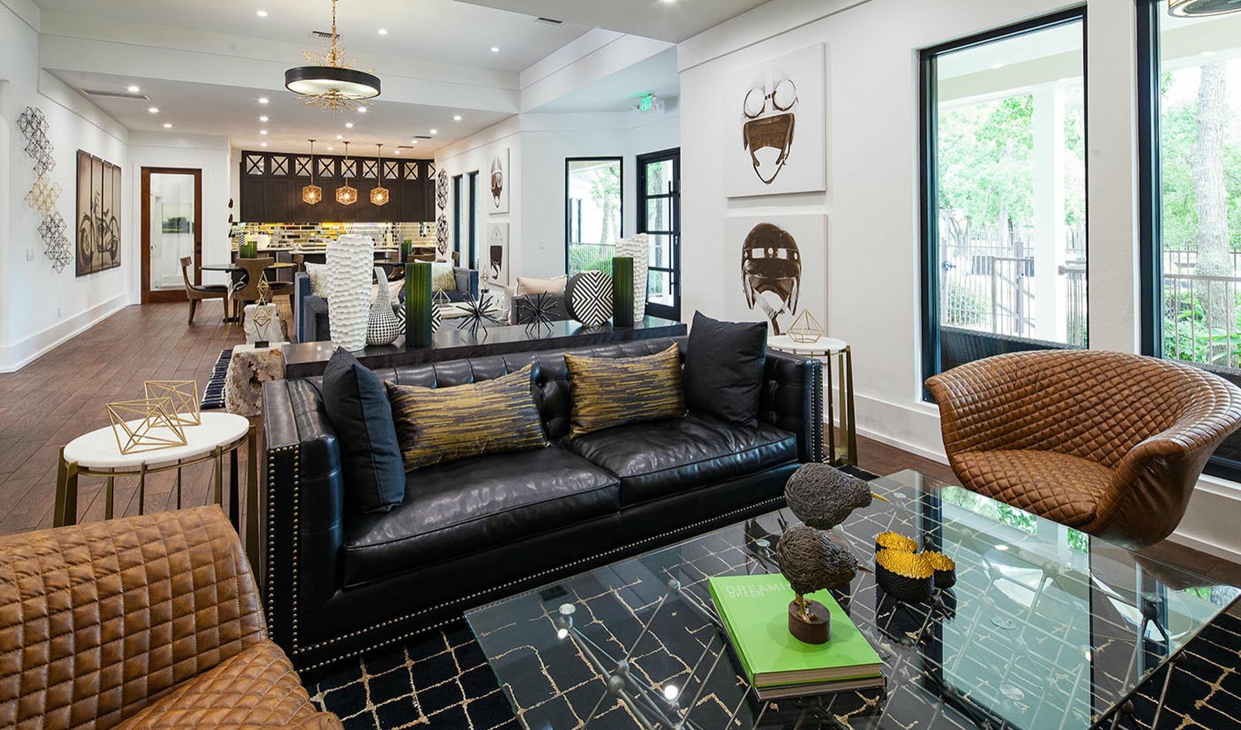 a lounge room with a black couch a table windows and a common area
